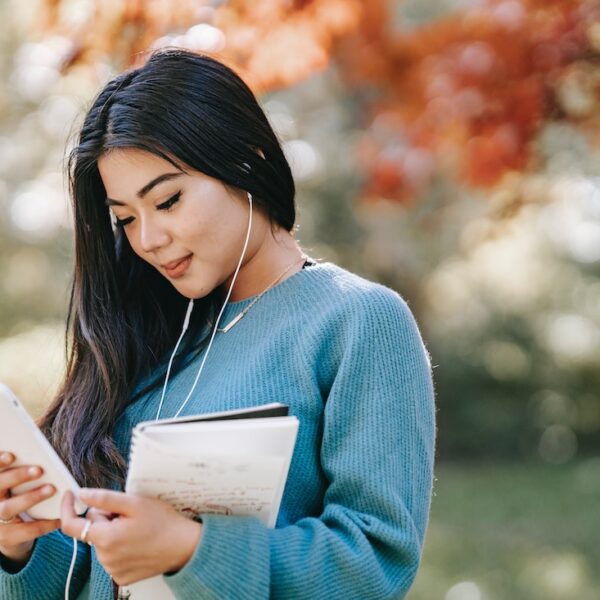 Woman in blue sweater listening to phone with earbuds