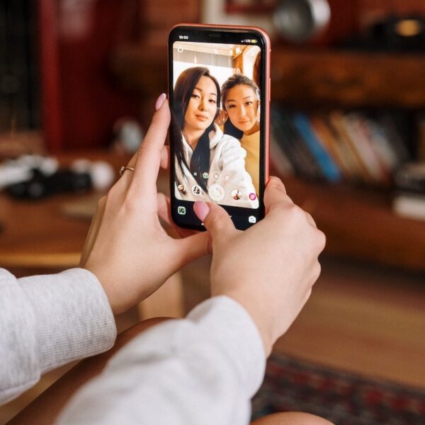 two girls holding phone filming Instagram Story