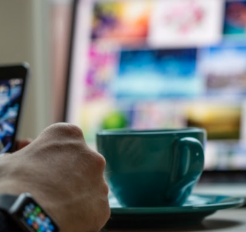 man on iPhone, drinking coffee from a teal mug