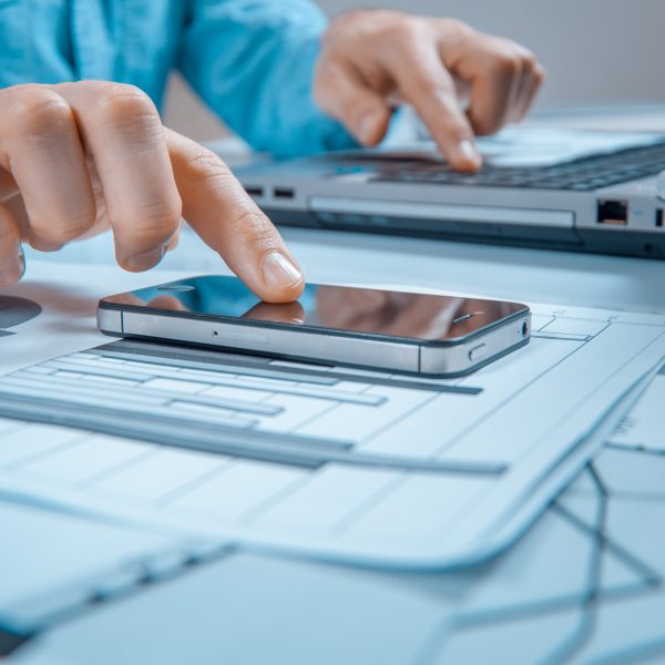 man looking up information on his phone to type on laptop