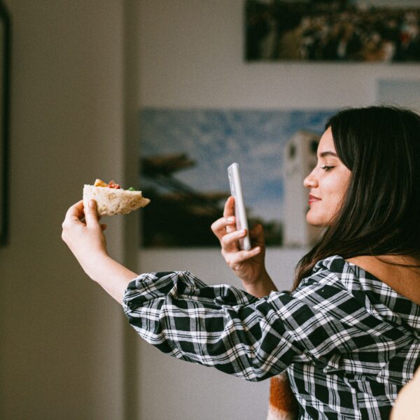 A woman uses her smartphone to take a picture of her upcoming meal