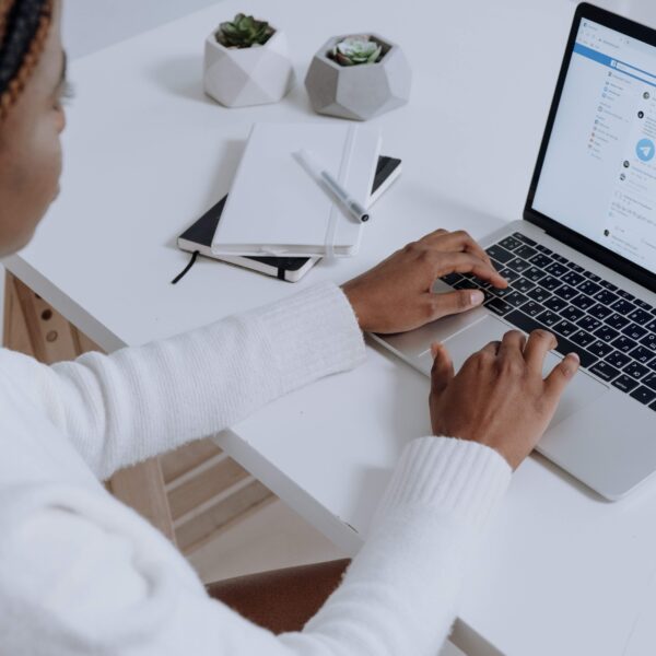 Woman in white shirt on computer updating Facebook