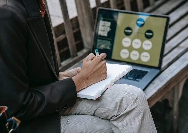 Businesswoman taking notes while looking at computer