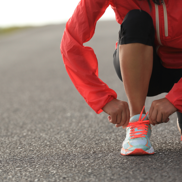 Lady runner in a red jacket bending down to tie her shoe