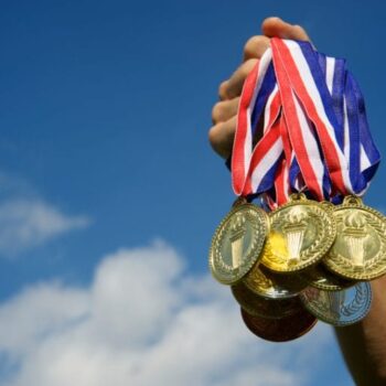 Outstretched hand holding a group of gold medals