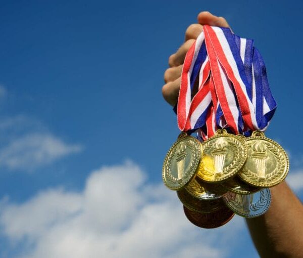 Outstretched hand holding a group of gold medals