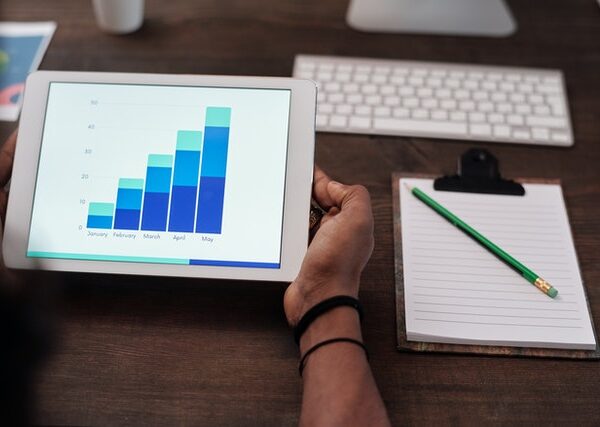 Screen displaying analytics next to notebook on desk