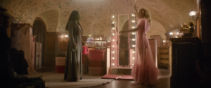 A screenshot of Cynthia Erivo as Elphaba and Ariana Grande as Glinda standing in a room across from one another in the Wicked Movie Official Trailer