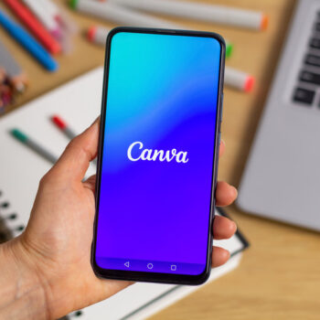 A smartphone displaying Canva in front of art supplies.