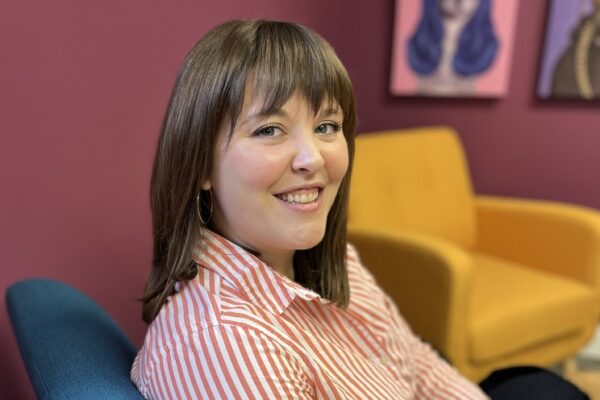 Lauren Vogel, APR sitting in a teal chair in Scooter Media's office.