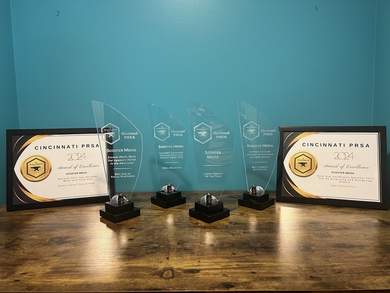 The 2024 Blacksmith Awards and Awards of Excellence won by Scooter Media, displayed on a table against a teal background.