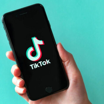 A smartphone displaying the TikTok logo set against a teal backdrop.